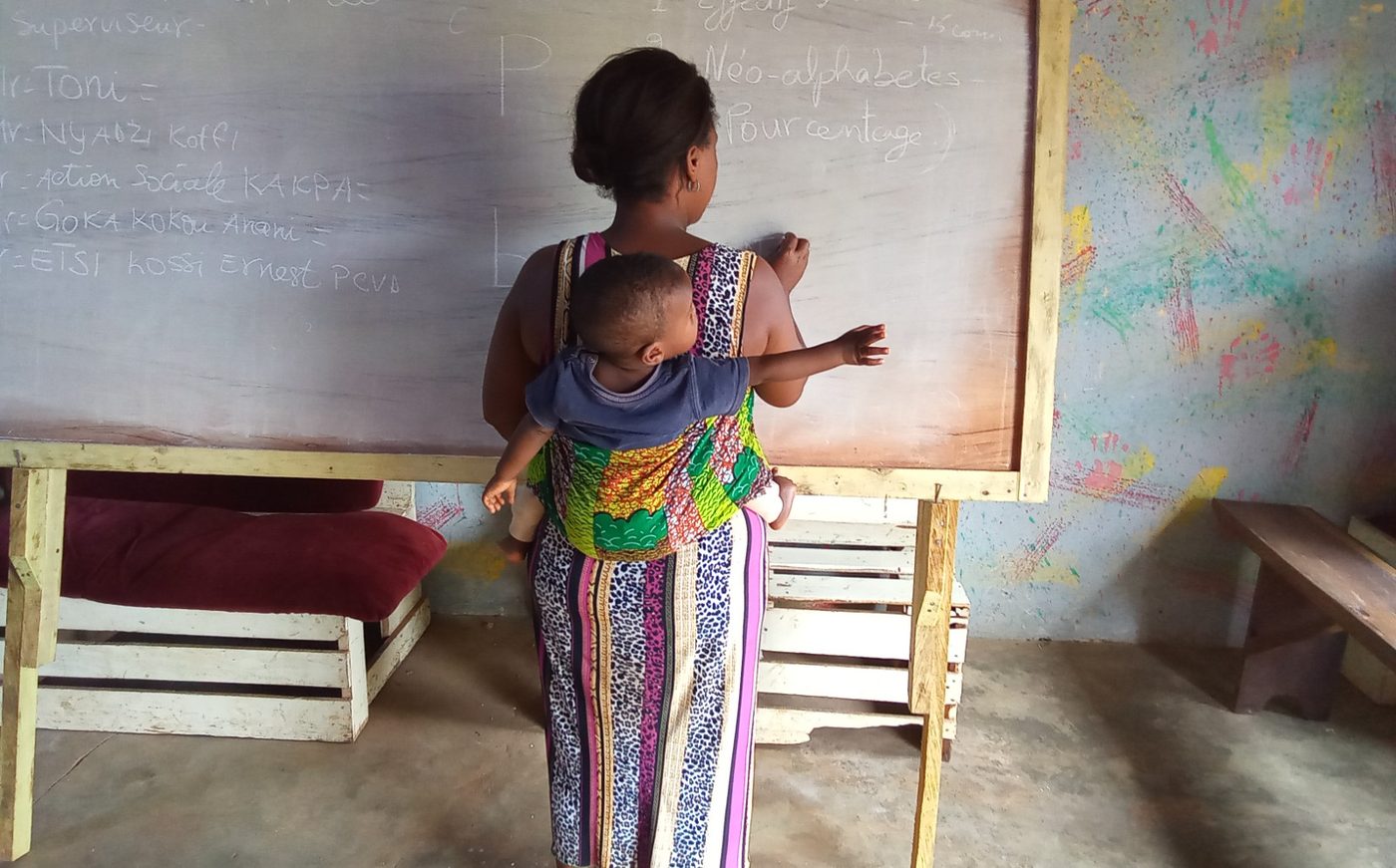 Une apprenante écrit au tableau devant sa classe dans un centre d'alphabétisation